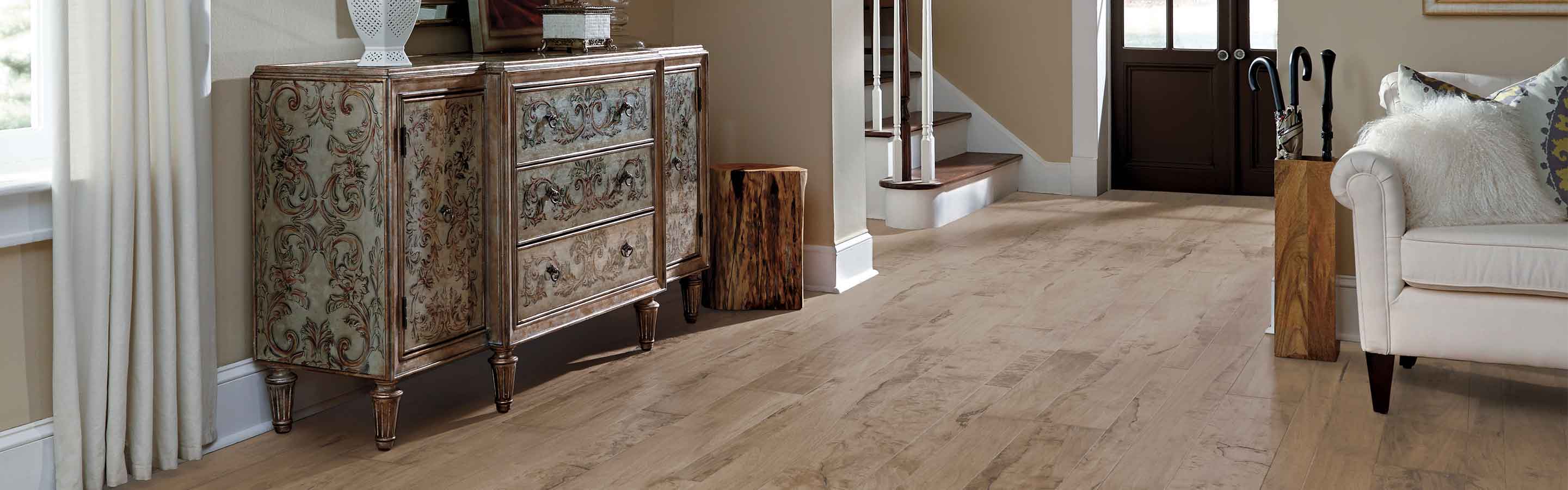 handscraped hardwood floors in entryway into modern living room with white couch and vintage sidetable